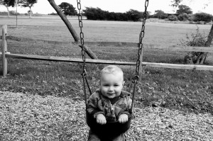 Little Boy happily swinging in B&W landscape