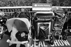 Kid sleeping in stroller near a stroller parking sign