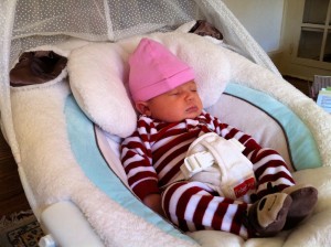Newborn baby in jammies sleeping in swing